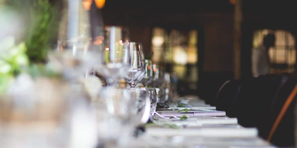 Zu Hause ist ein langer Tisch mit Gläsern und Tellern gedeckt. Zu Hause ist ein langer Tisch mit Gläsern und Tellern gedeckt.