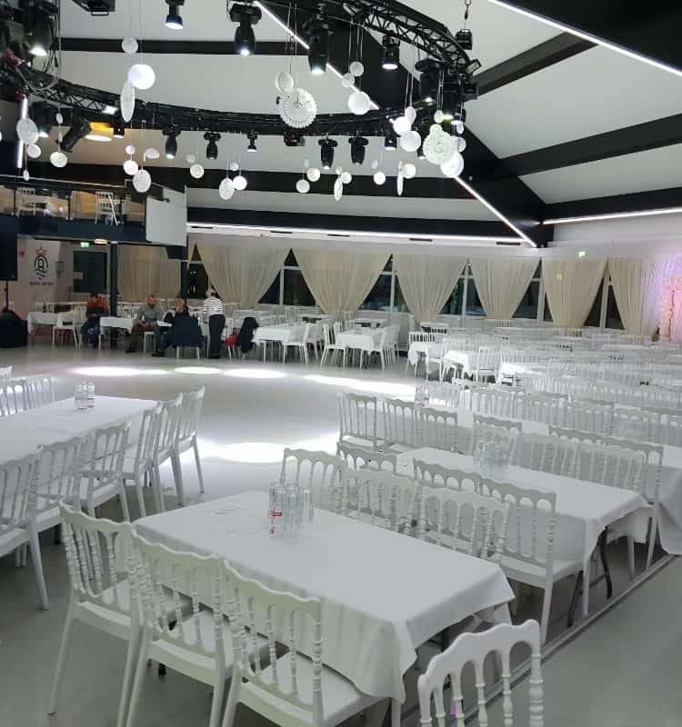 Ein großer Saal mit weißen Tischen und Stühlen.