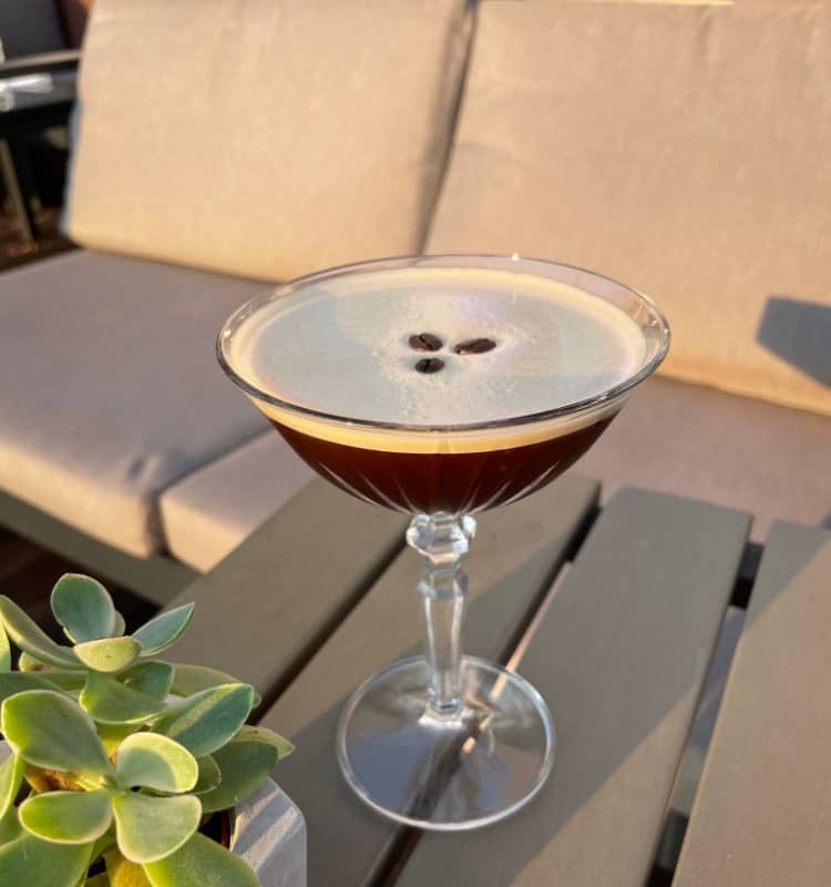 Ein Cocktail steht auf einem Tisch neben einer Pflanze.