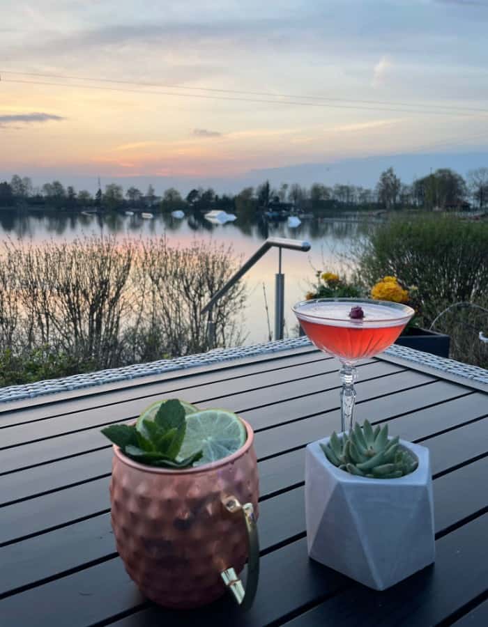 Ein Cocktail steht auf einem Tisch neben einem See.