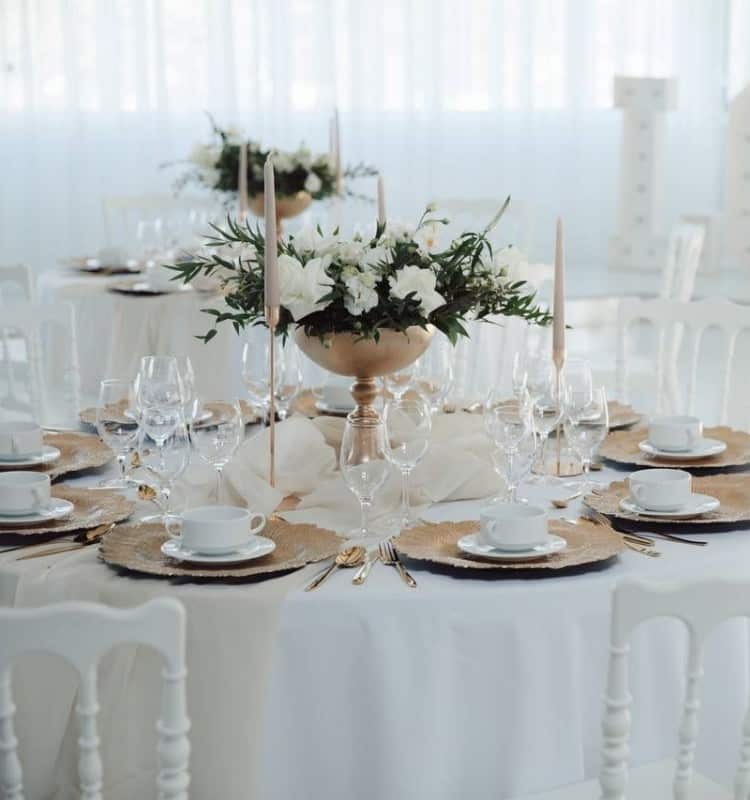 Ein Tischgedeck in Weiß und Gold für eine Hochzeitsfeier.