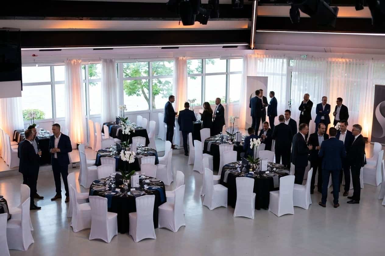 Festliches Firmenjubiläum mit Gästen im eleganten Saal von Royal am See und Blick auf den Friedberger Baggersee