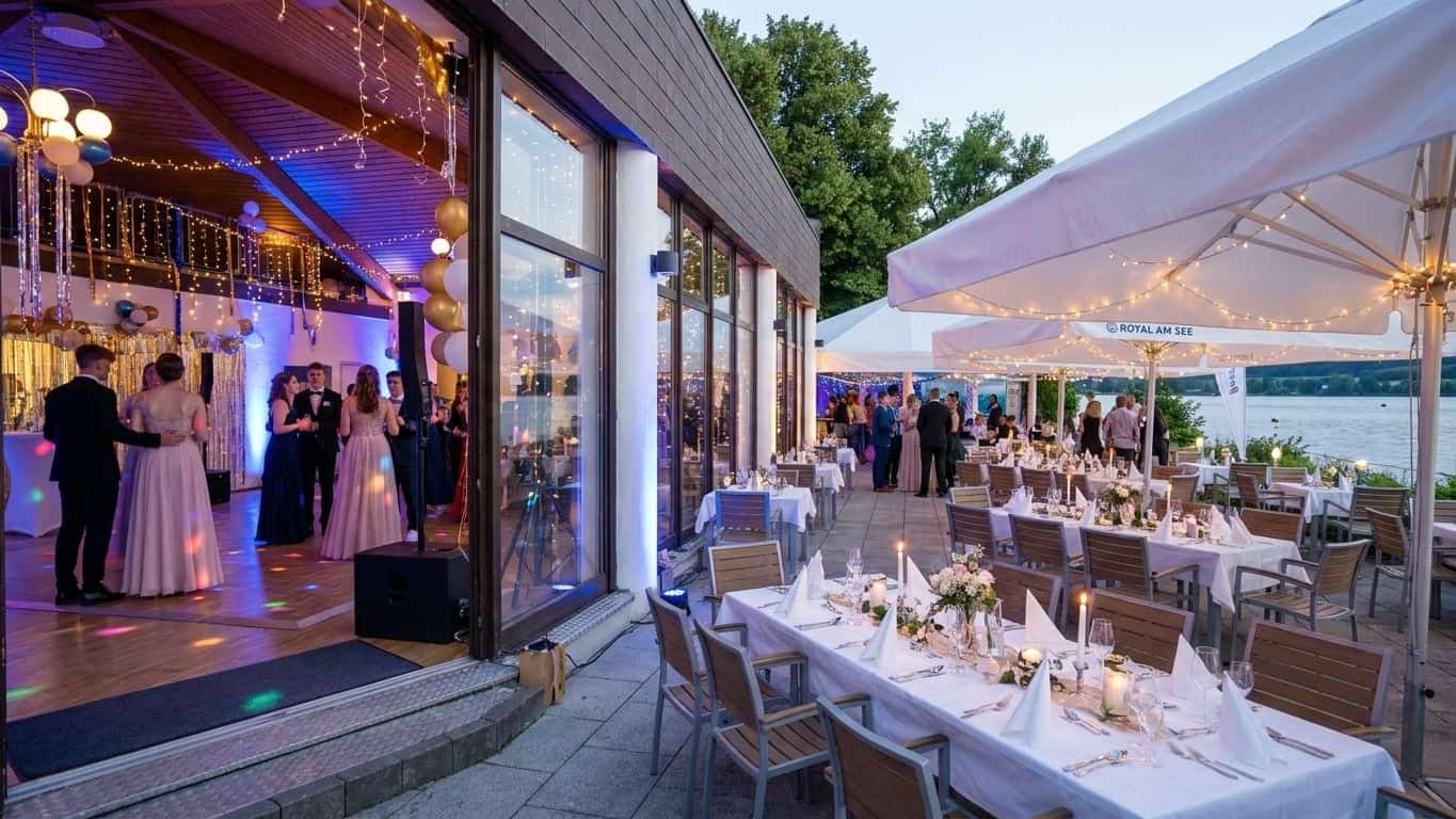 Modernes Eventgebäude mit großen Glasfenstern, das den See im warmen Abendlicht spiegelt