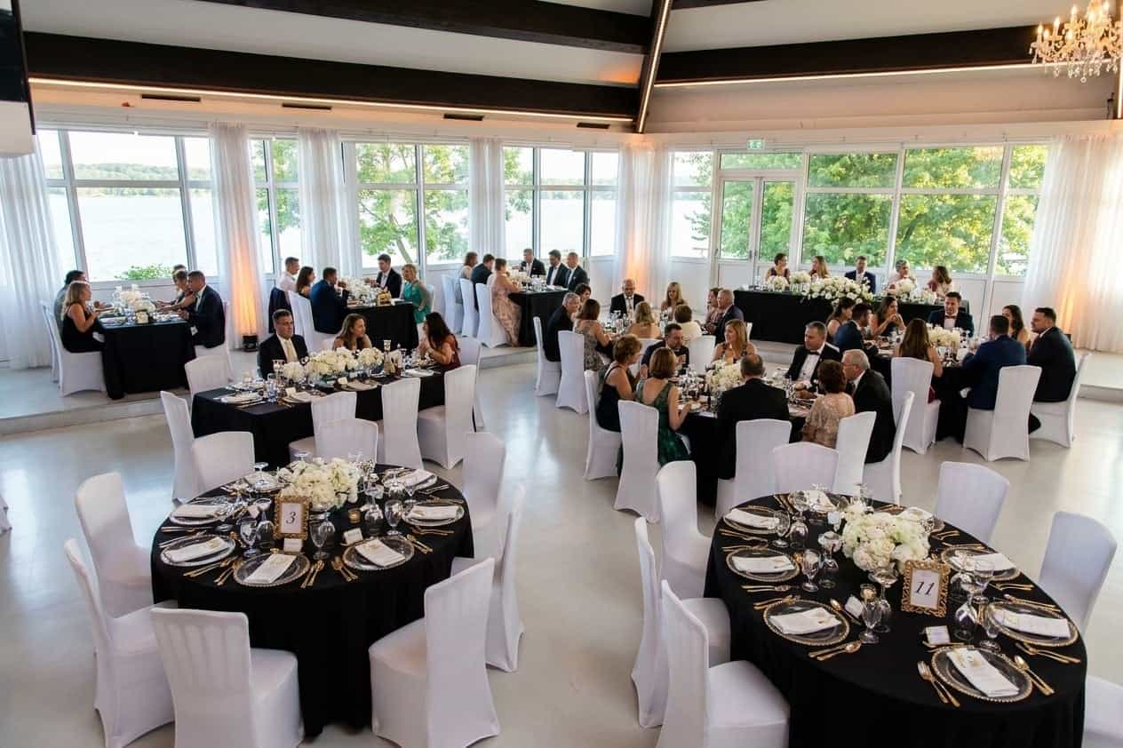 Lange Banketttafel elegant dekoriert mit Kerzen und Blumen im Eventsaal mit Seeblick