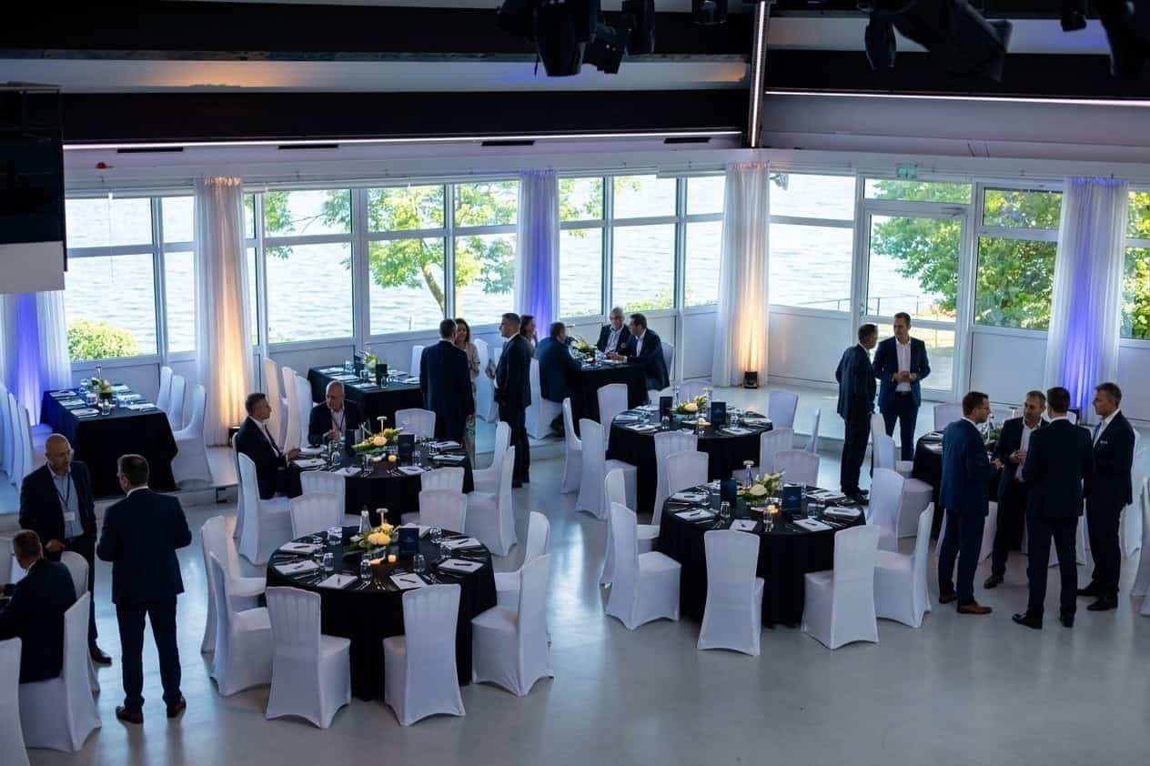 Professionelles Firmendinner-Setup in U-Form mit Seeblick